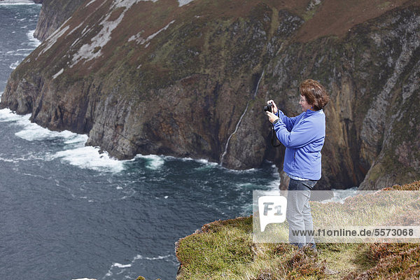 Frau fotografiert mit digitaler Kompaktkamera  Klippen von Slieve League  County Donegal  Irland  Europa