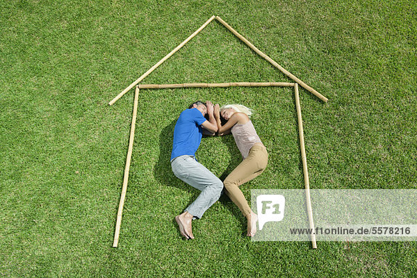 Couple lying on grass within outline of house  high angle view