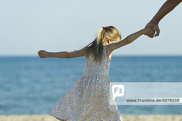 Mädchen geht am Strand spazieren  hält die Hand der Eltern  abgeschnitten