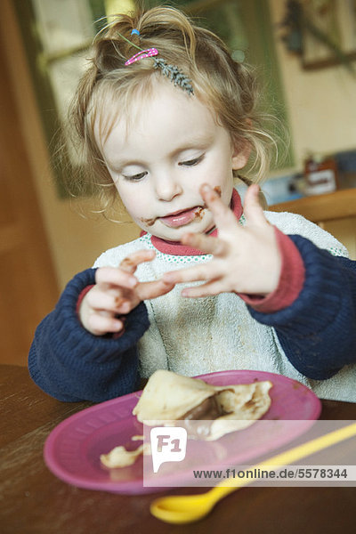 Kleinkind spielt mit den Händen beim Essen von Snacks