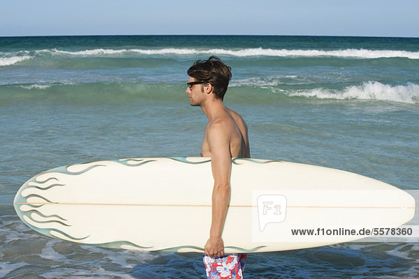 Junger Mann mit Surfbrett  Seitenansicht