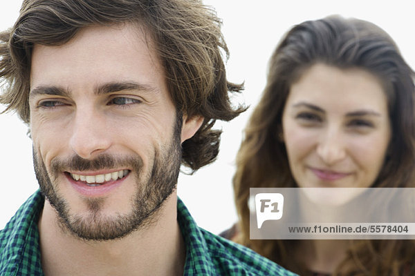 Junger Mann lächelnd  junge Frau im Hintergrund