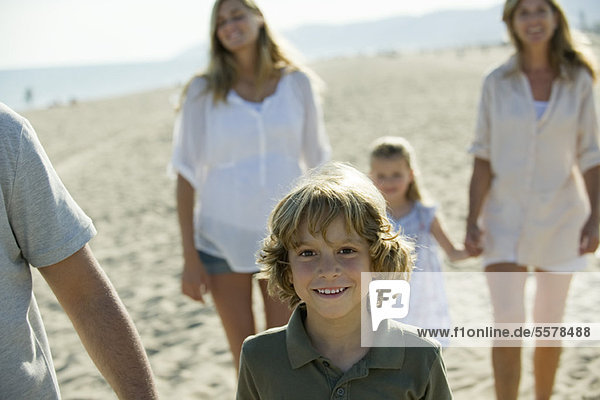 Junge  der mit seiner Familie am Strand spazieren geht.