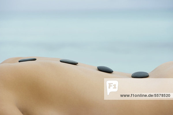 Nackte Frau erhält Hot-Stone-Massage  Mittelteil