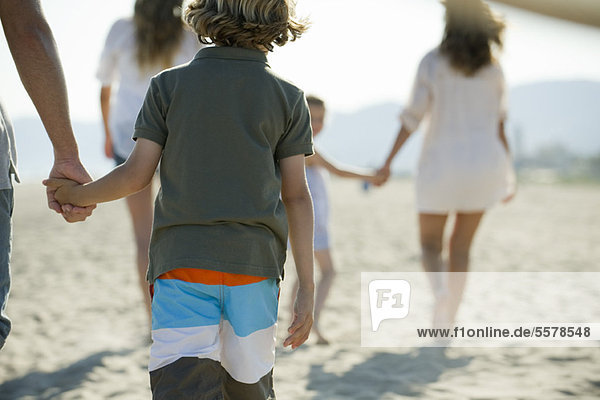 Junge am Strand mit seiner Familie  hält Vaters Hand  Rückansicht