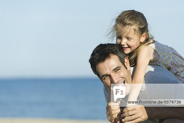 Father giving young daughter piggyback ride