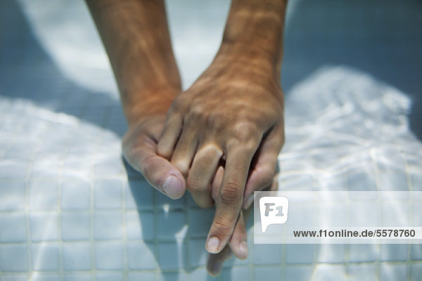 Paar hält Hände unter Wasser  abgeschnitten