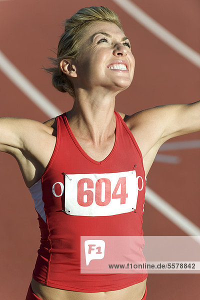 Woman running on track  looking up victoriously