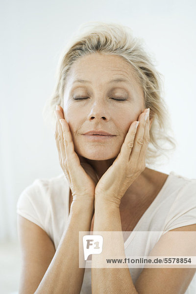 Mature woman touching her face  eyes closed  portrait