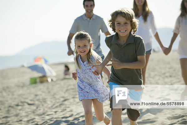 Kinder laufen am Strand  Familie im Hintergrund