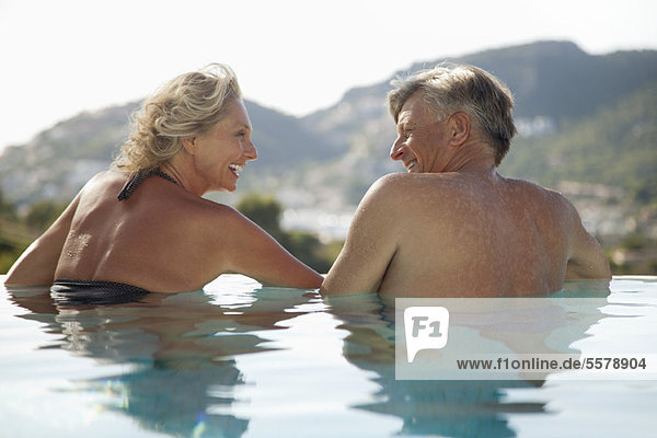 Reife Paare entspannen sich gemeinsam im Pool  Rückansicht