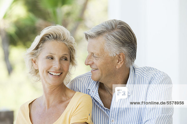 Mature couple smiling at each other outdoors