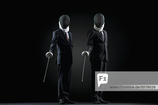 Businessmen standing with fencing masks and foils