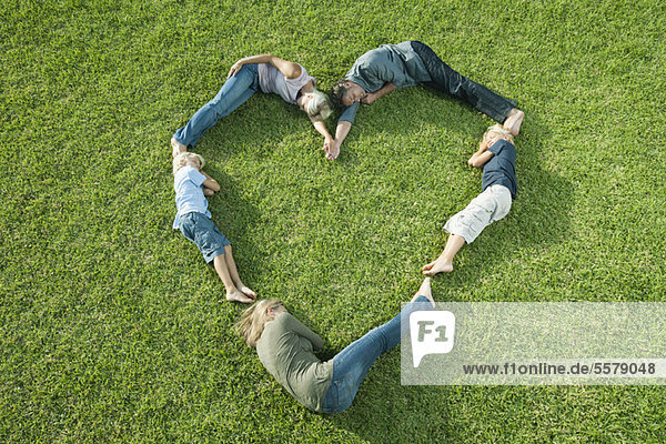 People lying on grass positioned in shape of heart