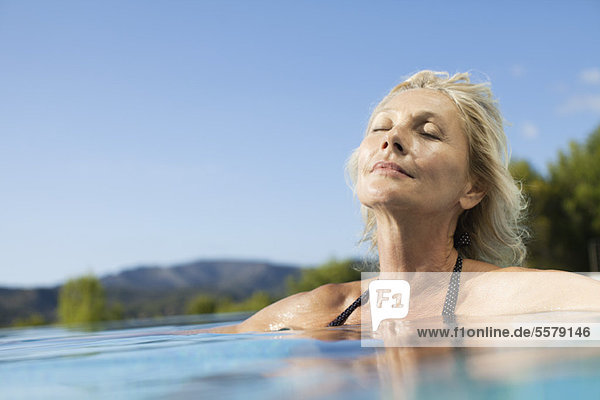 Mature woman relaxing in pool with eyes closed