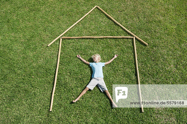 Boy lying on grass within outline of house  high angle view