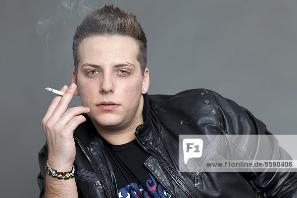 Junger Mann in Lederjacke raucht  Portrait