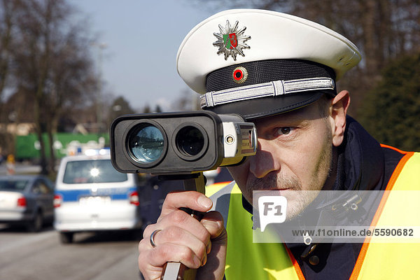 Police officer with a laser speed measuring device  speed check marathon of the police in North Rhine-Westphalia on 10 February 2012  photocall  start of a long-term campaign against speeding in North Rhine-Westphalia  Germany  Europe