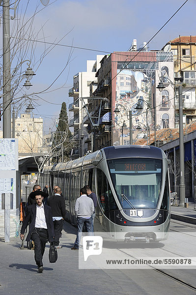 Straßenszene auf der Jaffa-Straße mit einem orthodoxen Juden  der neuen Straßenbahn  Stadtbahn Jerusalem und einem Wandgemälde auf dem die Straßenbahn gemalt ist  Jerusalem  Israel  Naher Osten  Vorderasien