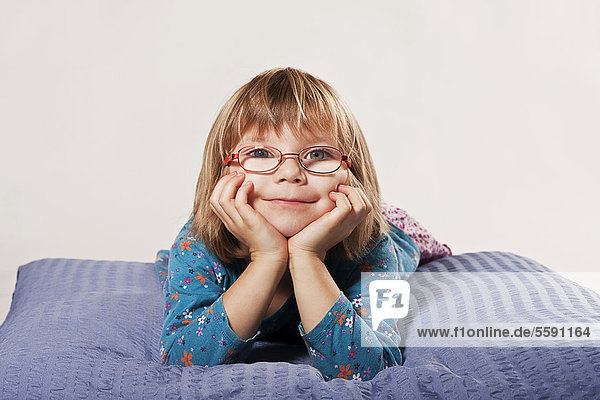 Girl with glasses lying on a pillow