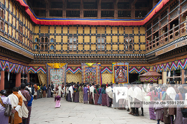 Tibetan Buddhist festival  people wearing the traditional Gho robe standing in a queue  Rinpung Dzong Monastery and Fortress  courtyard  Paro  Himalayas  Bhutan  South Asia  Asia