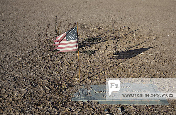 Eine amerikanische Flagge im Memory Gardens Cemetery and Memorial Park der Friedhof befindet sich in Zwangsvollstreckung und die Bewässerung wurde abgeschnitten der Sand beginnt bereits einige der Grabsteine zu bedecken Brawley Kalifornien USA