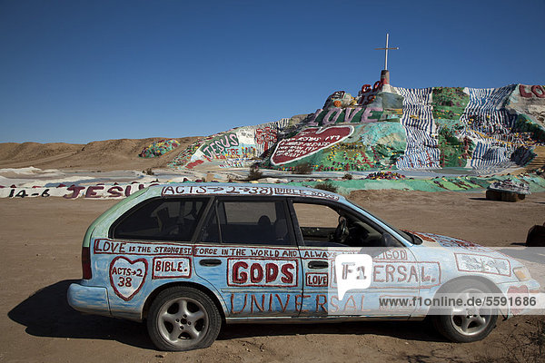 Ein bemaltes Auto vor dem Salvation Mountain  einem Wüstenhügel bedeckt mit religiösen Botschaften  von Leonard Knight erschaffen  Niland  Kalifornien  USA