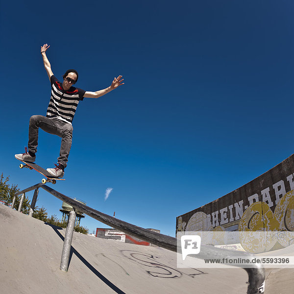 Germany  North Rhine-Westphalia  Duisburg  Skateboarder performing trick on ramp at skateboard park