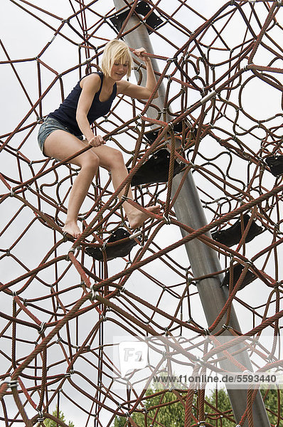 Germany  North Rhine-Westphalia  Duesseldorf  Young woman climbing frame in playground
