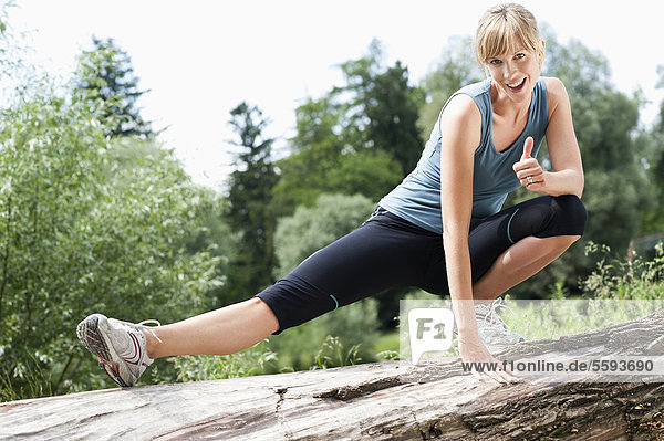 Mid adult woman exercising on tree stump  smiling  portrait