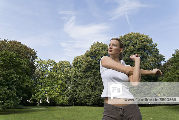 Deutschland  Nordrhein-Westfalen  Düsseldorf  Junge Frau beim Stretching im Park