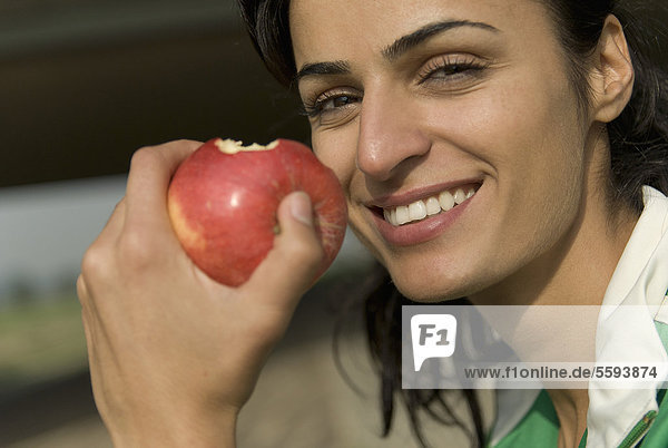Germany  North Rhine-Westphalia  Duesseldorf  Young woman eating apple  smiling  portrait