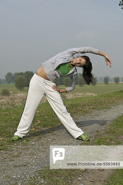 Germany  North Rhine-Westphalia  Duesseldorf  Young woman doing exercise in field