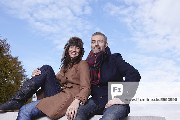 Germany  Cologne  Couple sitting on bridge  smiling  portrait