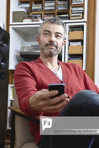 Mature man sitting on chair with cell phone  smiling