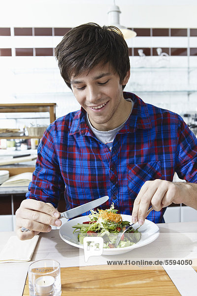 Young man eating salad  smiling