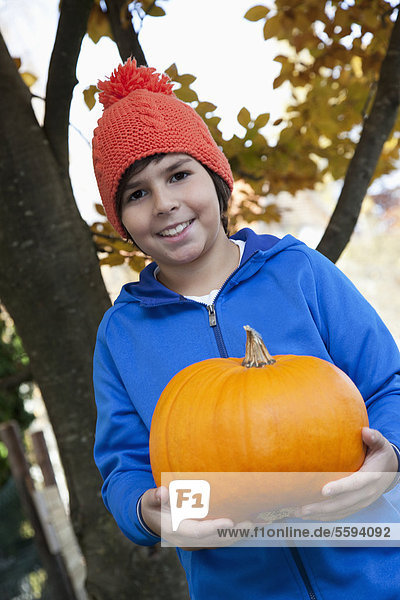 Boy holding pumpkin  smiling  portrait