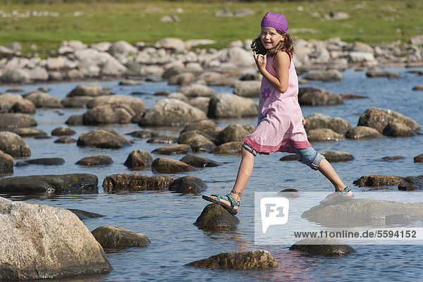 Schweden  Molle  Mädchen beim Balancieren auf Felsen im Wasser