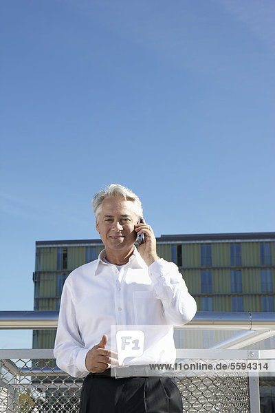Deutschland  Bayern  München  Geschäftsmann am Telefon  lächelnd  Portrait