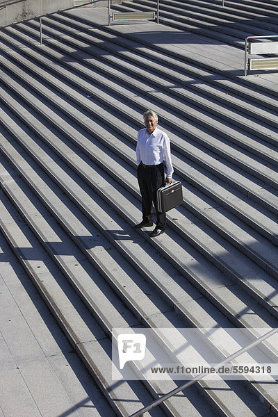 Deutschland  Bayern  München  Geschäftsmann auf Treppe stehend mit Aktentasche  Portrait