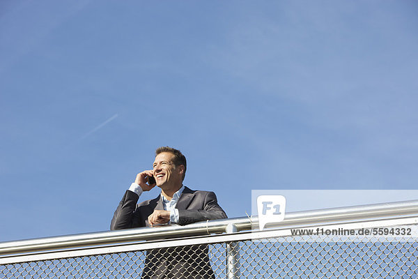 Deutschland  Bayern  München  Geschäftsmann im Gespräch am Handy  lächelnd