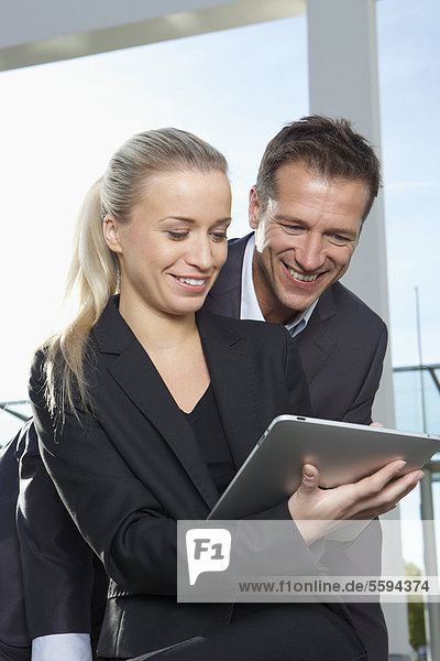 Germany  Bavaria  Munich  Business people using digital tablet  smiling