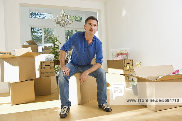 Mature man sitting on cardboard box