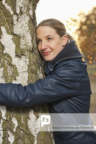 Mittlere erwachsene Frau umarmt Baum  Nahaufnahme