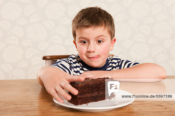 Boy reaching for chocolate cake