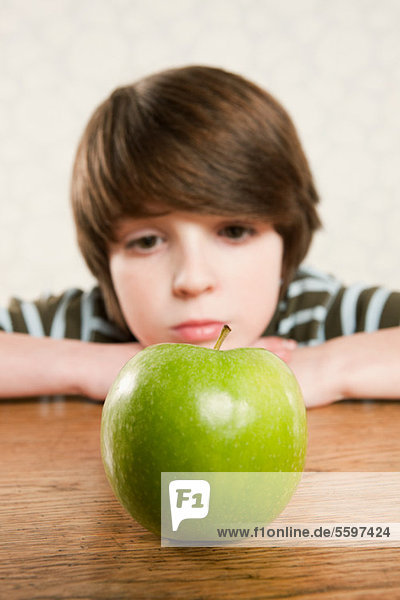 Junge  der auf einen Apfel starrt.