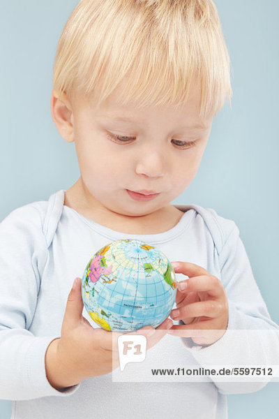 Kleiner Junge schaut auf den kleinen Globus