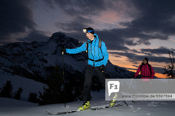 Two ski mountaineers in the Dolomites in winter at dusk  Italy