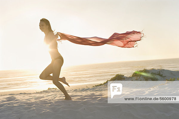 Woman running with sarong on beach