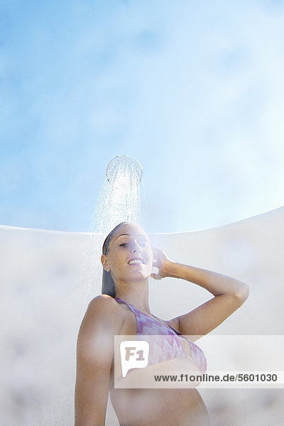 Frau im Bikini beim Duschen im Freien